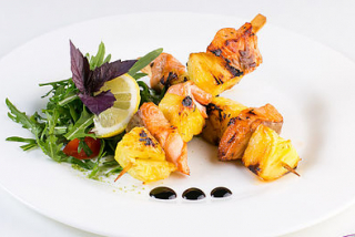 Skewers of salmon with pineapple and salad of arugula
